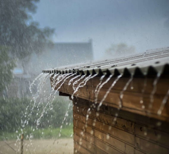 Image of rain pouring off roof protecting firewood